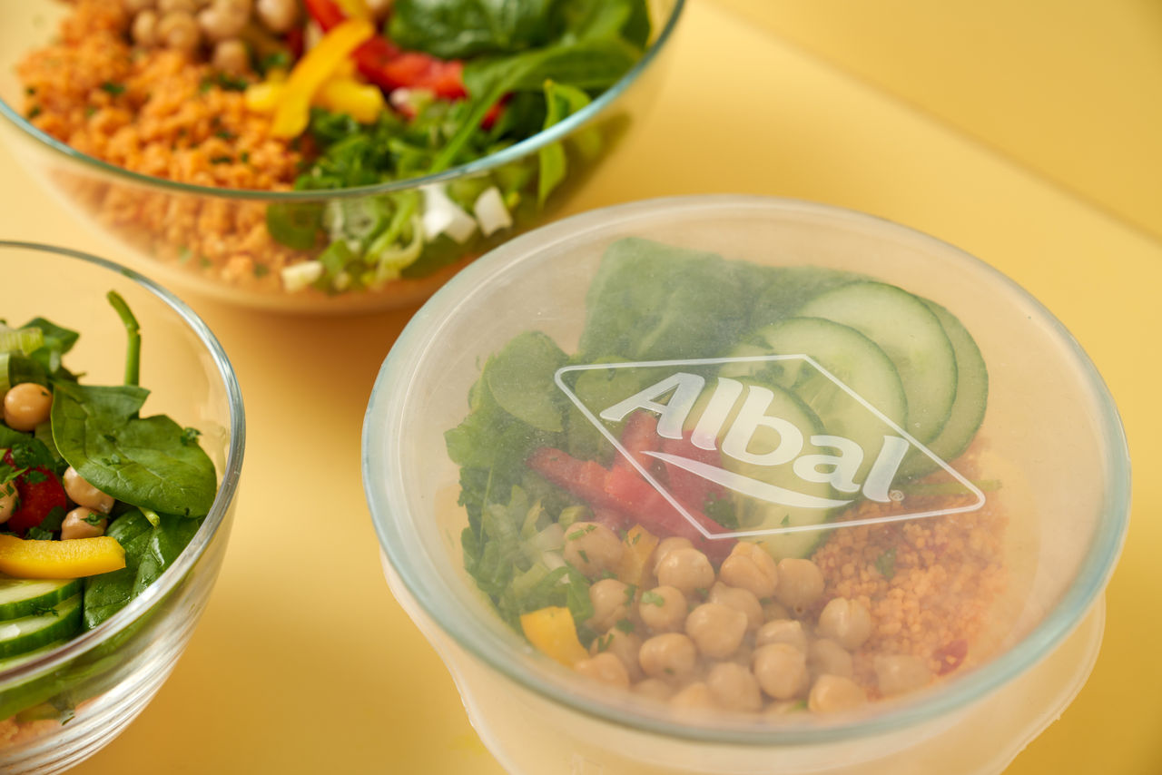 La pomme de terre enveloppée dans du papier d’aluminium repose sur une table en bois devant un gril